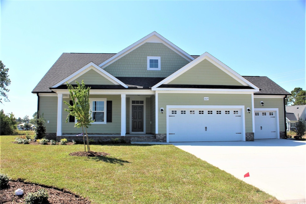Craftsman-style house featuring a garage, driveway, a front lawn, a shingled roof, and covered porch