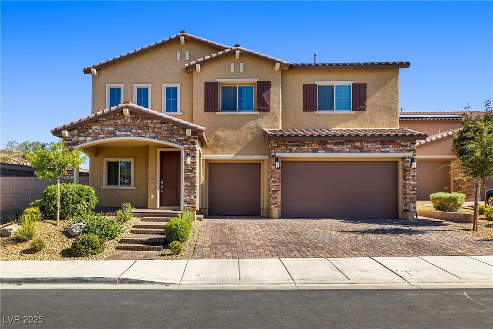 Mediterranean / spanish-style home featuring stucco siding, decorative driveway, an attached garage, a tiled roof, and stone siding