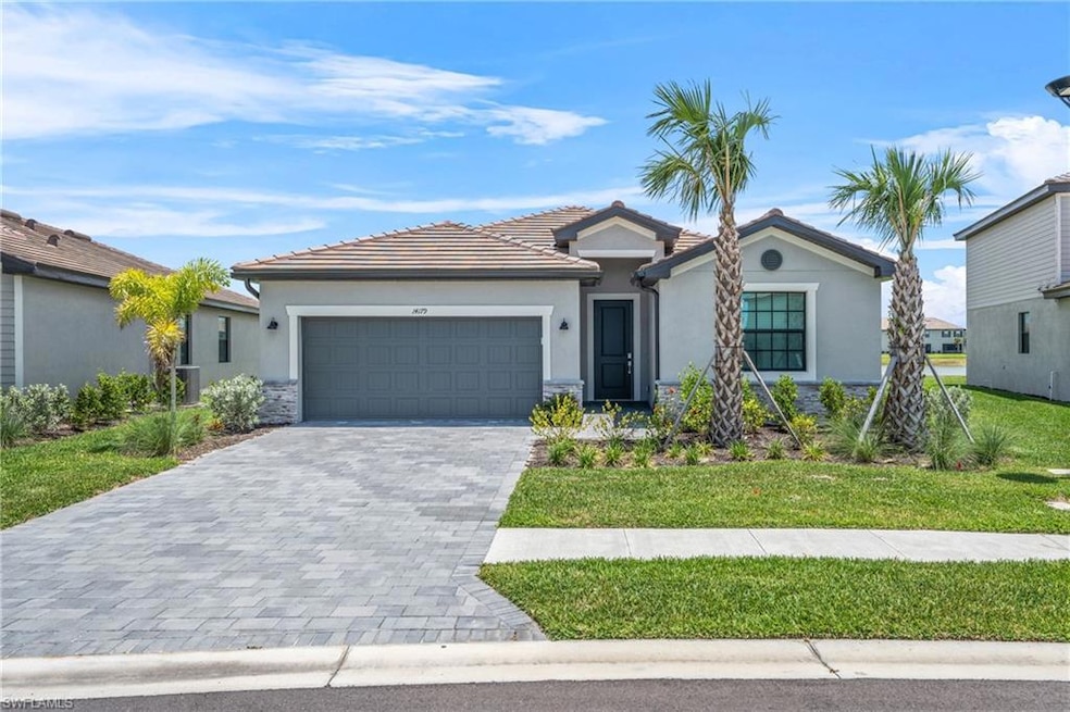 Ranch-style home featuring stucco siding, an attached garage, decorative driveway, a tile roof, and a front yard