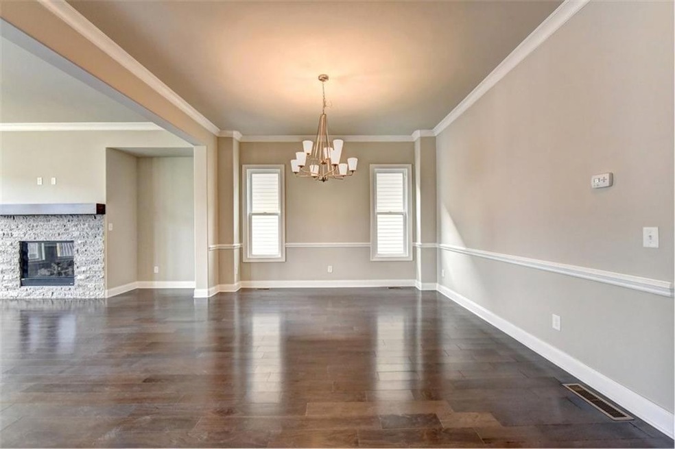 Dining area featuring crown molding, dark hardwood / wood-style flooring, a fireplace, and an inviting chandelier
