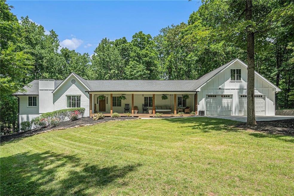 View of front of house featuring board and batten siding, an attached garage, a porch, a front lawn, and concrete driveway