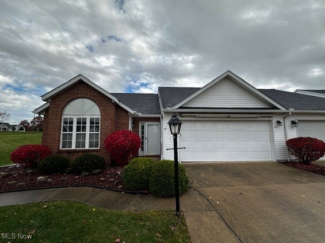 Ranch-style home featuring concrete driveway, an attached garage, and brick siding