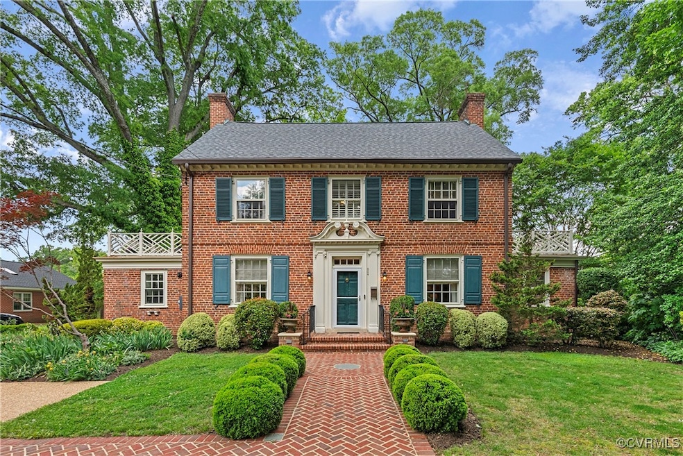 Colonial house with a chimney, a front yard, brick