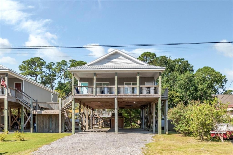 Beach home featuring gravel driveway, a front lawn, stairway, a carport, and a deck