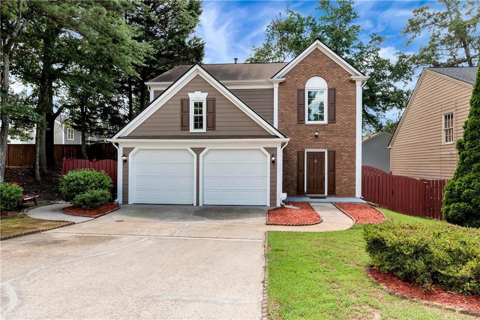 Traditional-style house featuring brick siding, driveway, and an attached garage