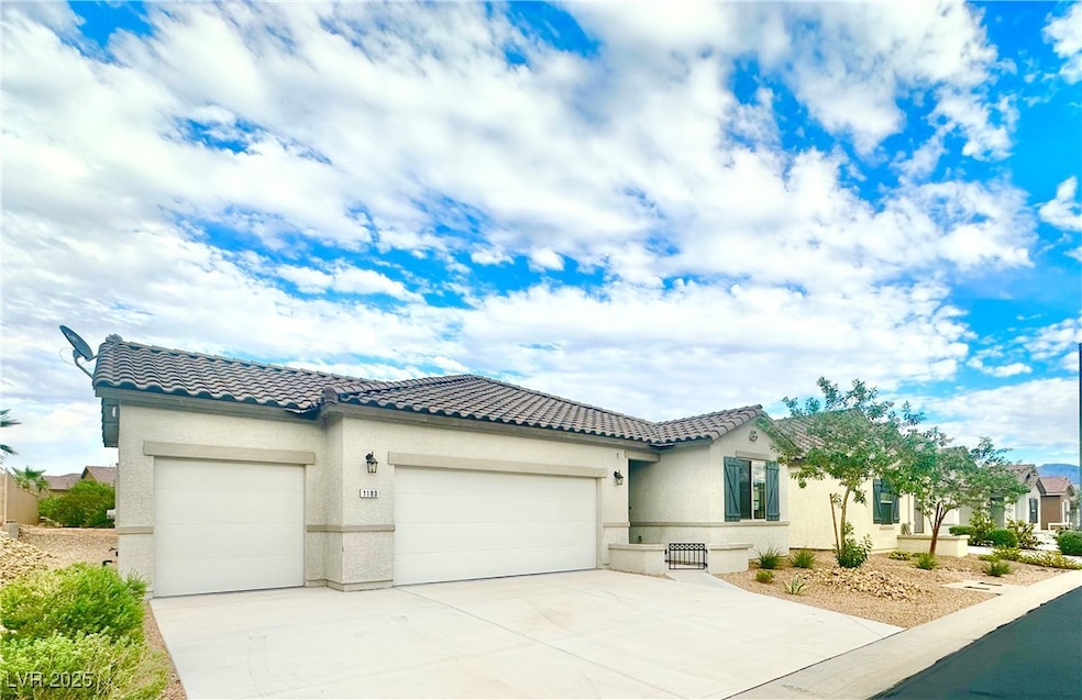 View of front facade featuring an attached garage, a tile roof, stucco siding, and concrete driveway
