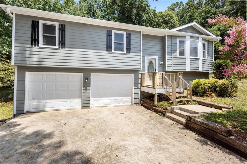 Raised ranch featuring an attached garage and driveway