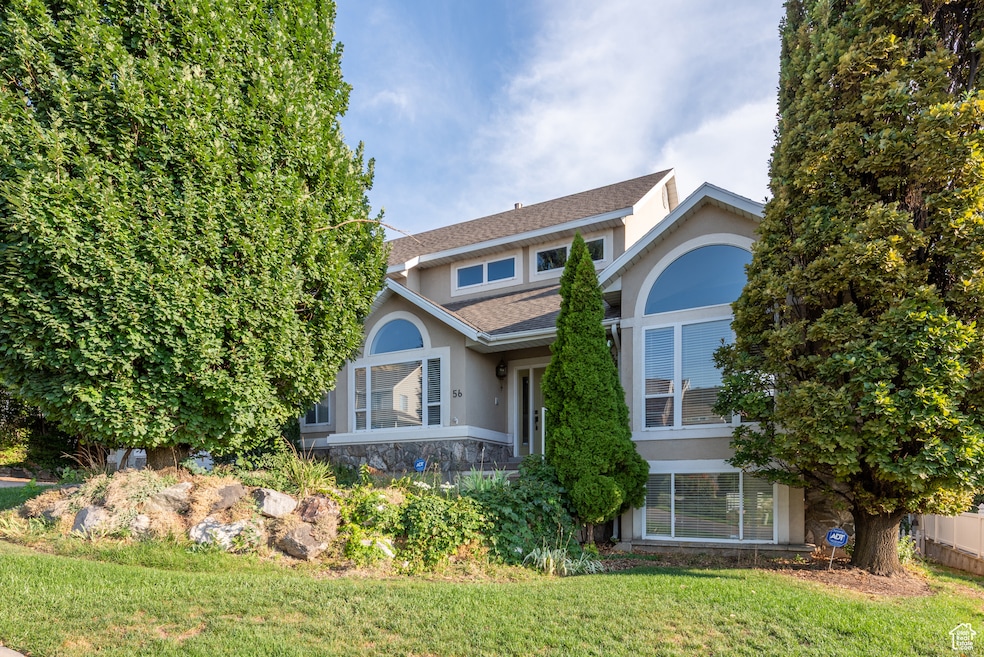 View of front of home featuring stucco siding, a front yard, and roof with shingles