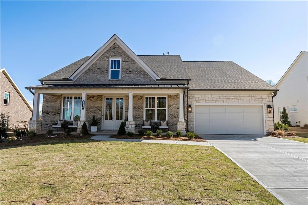 View of front of home featuring a front lawn, driveway, french doors, an attached garage, and brick siding