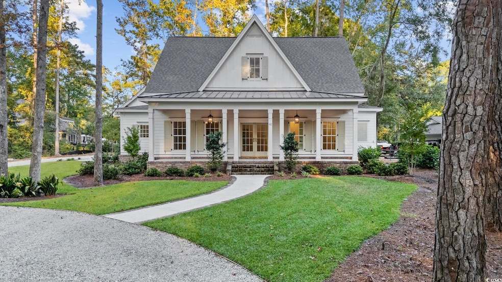 View of front facade featuring a standing seam roof, covered porch, a metal roof, roof with shingles, and a front yard