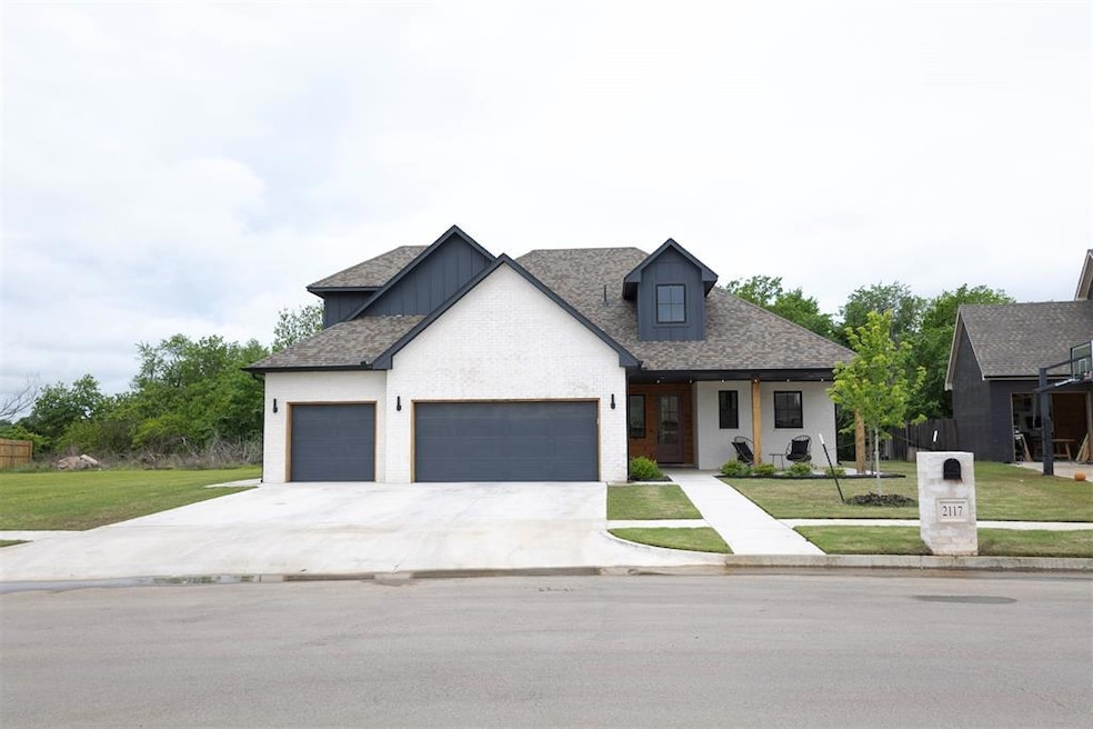 Modern farmhouse style home featuring an attached garage, a front lawn, driveway, board and batten siding, and roof with shingles