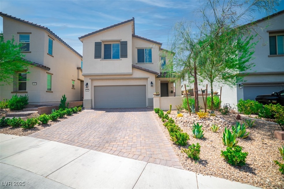 View of front of house featuring decorative driveway, stucco siding, and an attached garage