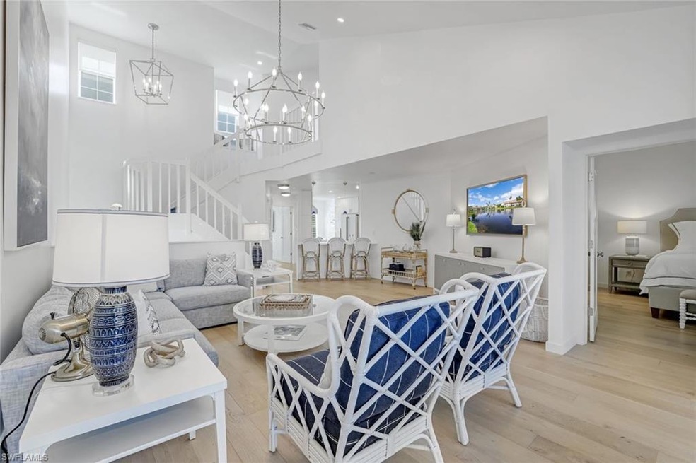 Living room with light wood-style floors, stairs, a towering ceiling, and recessed lighting