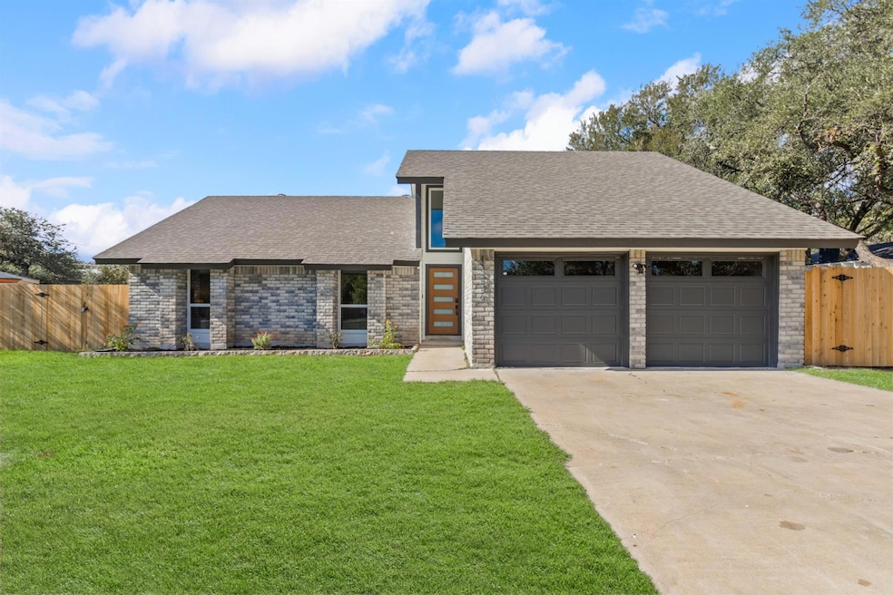 View of front facade featuring roof with shingles, brick siding, driveway, a garage, and a gate