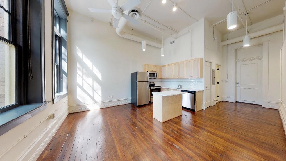 Kitchen featuring stainless steel appliances, dark hardwood / wood-style floors, a towering ceiling, tasteful backsplash, and ceiling fan