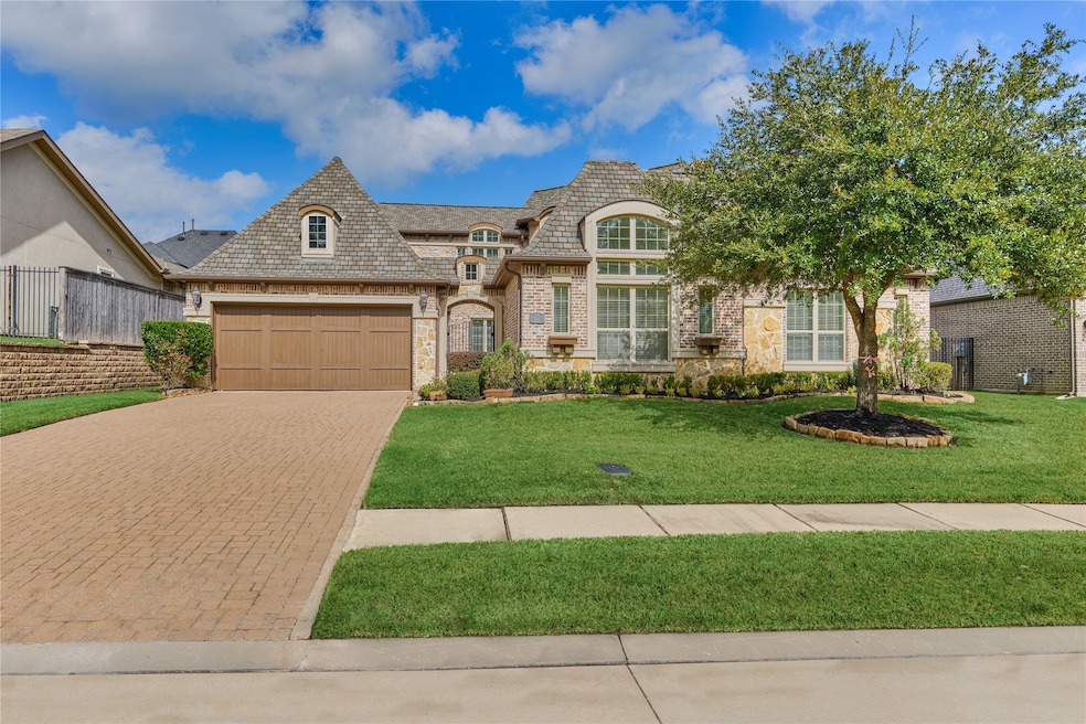 Charming two-story brick and stone home with a spacious driveway and two-car garage. Features beautiful landscaping with a well-maintained lawn and mature tree. Large windows offer plenty of natural light, enhancing the home's curb appeal.