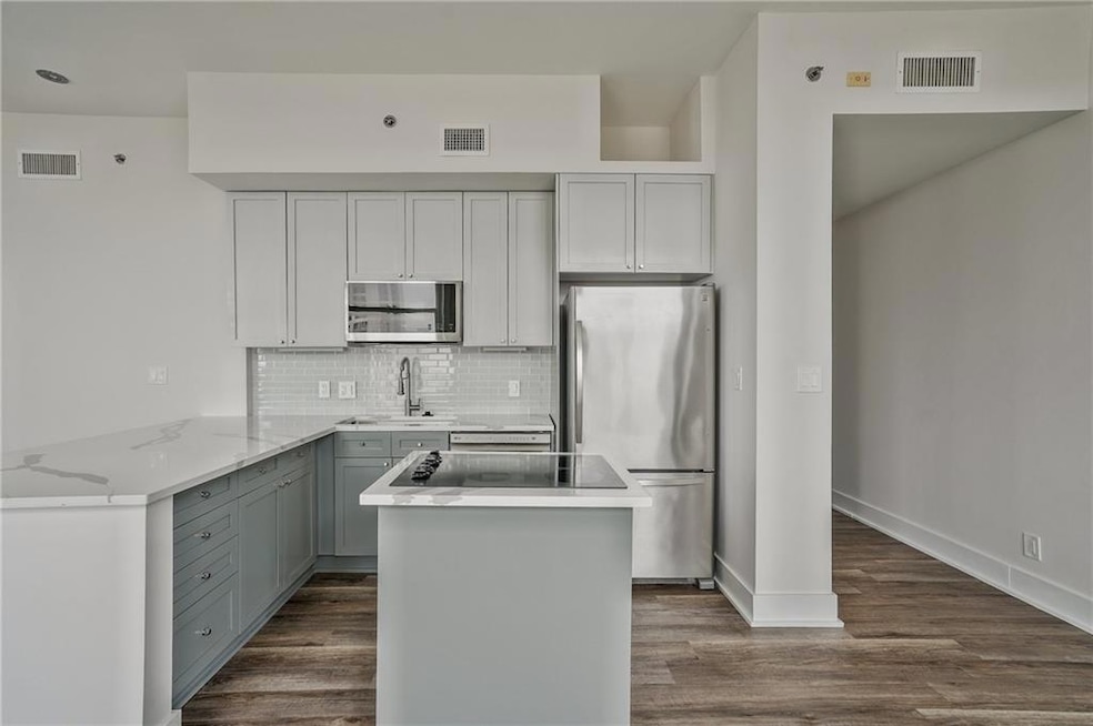Kitchen featuring stainless steel appliances, a sink, gray cabinetry, tasteful backsplash, and dark wood-style flooring