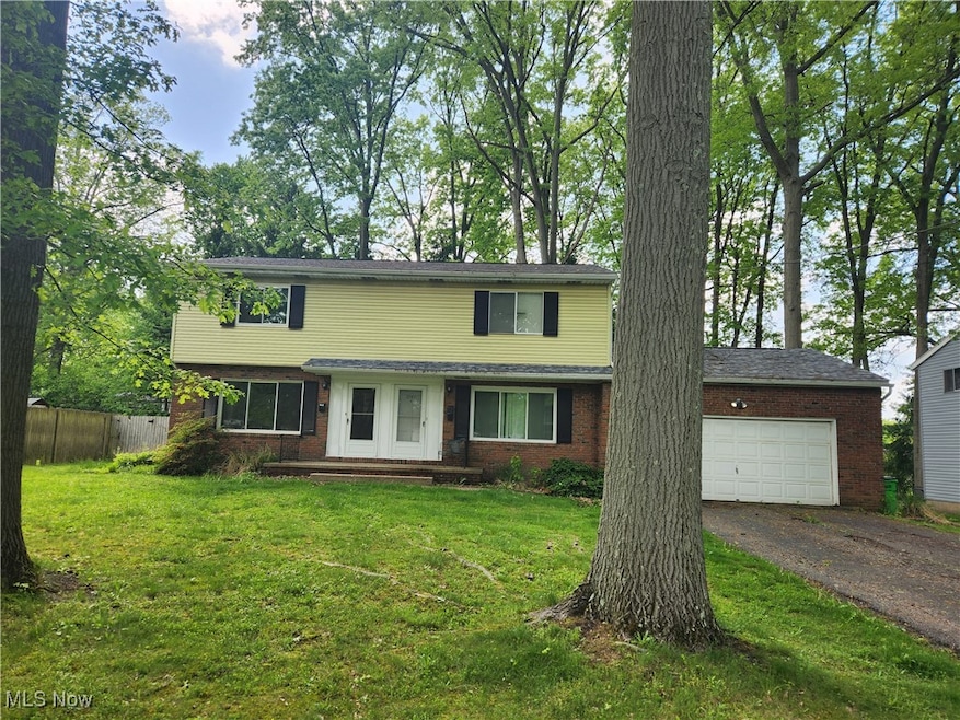 View of front facade featuring dirt driveway, brick siding, and a garage