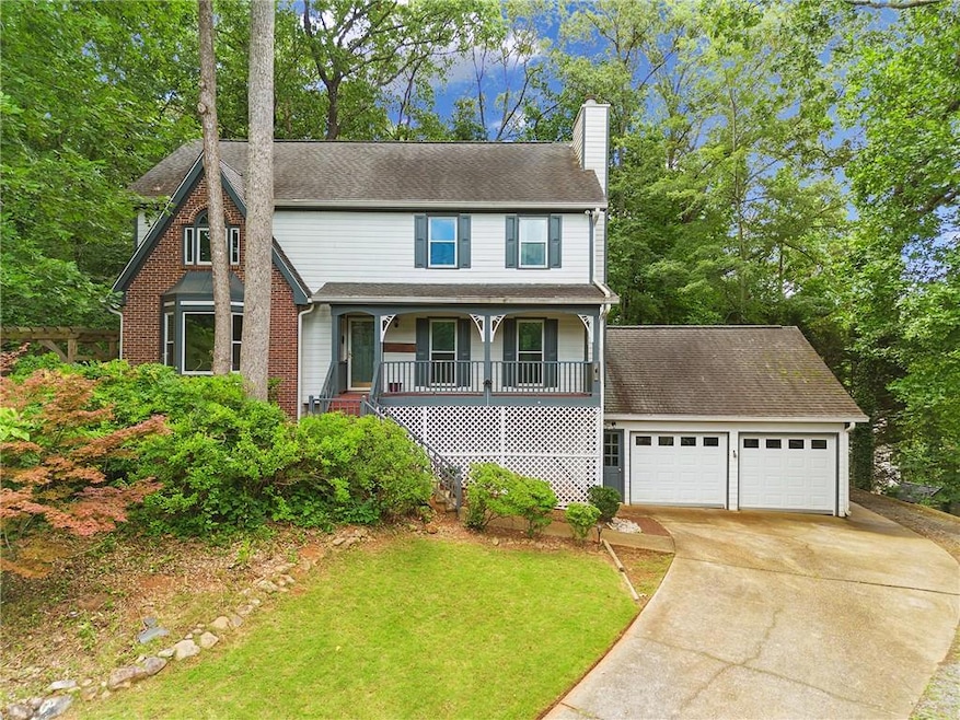 View of front of house with a chimney, a porch, concrete driveway, a garage, and a front yard