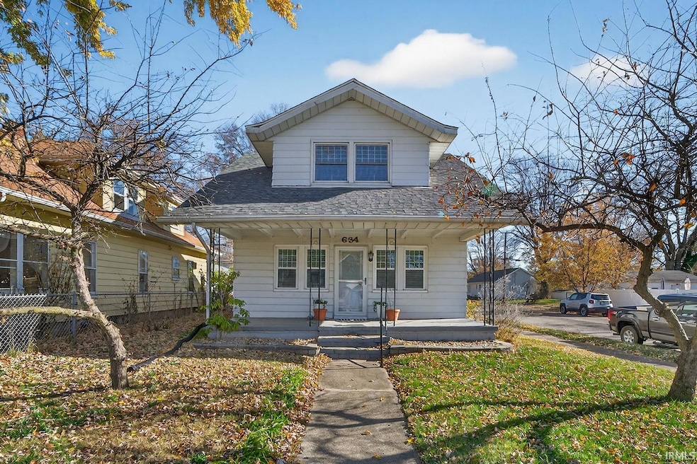 Bungalow-style house featuring covered porch, roof with shingles, and a front yard