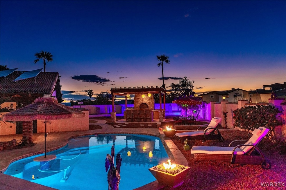 Pool at dusk featuring an outdoor fireplace, a per