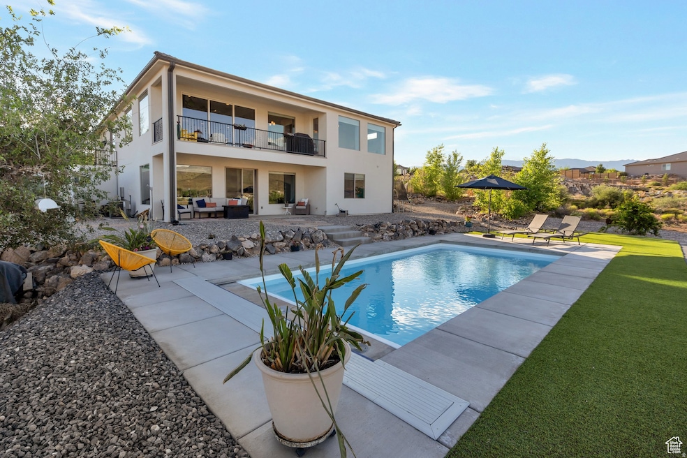 Back of property featuring a patio, an outdoor pool, stucco siding, an outdoor living space, and a balcony