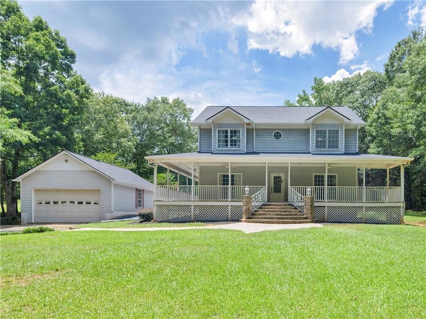 Farmhouse featuring covered porch, a detached garage, a front lawn, and an outbuilding