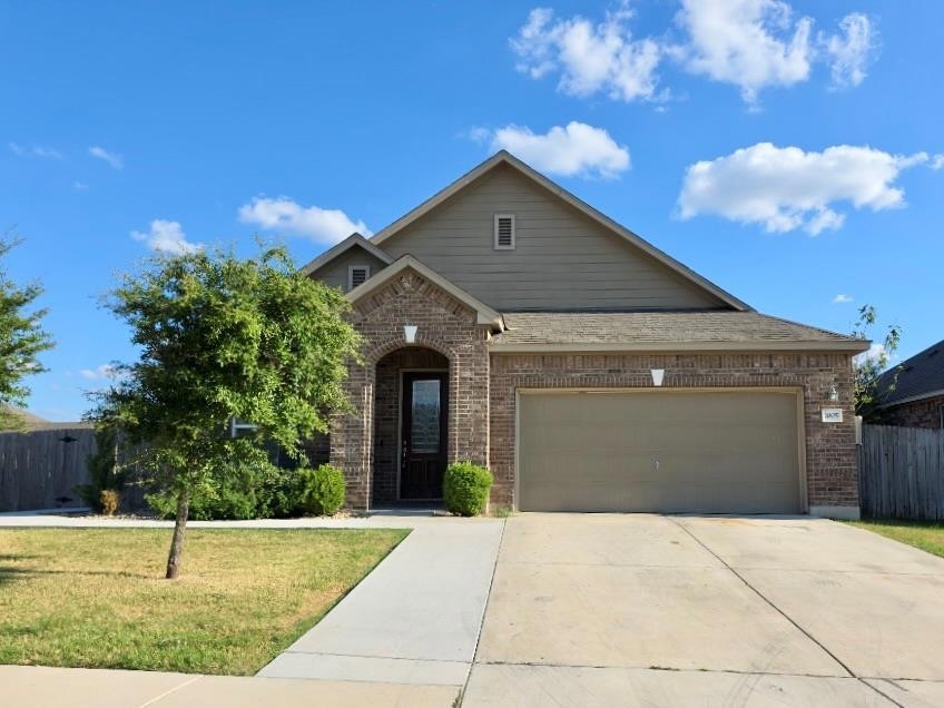 View of front of home with brick siding, driveway, and a garage
