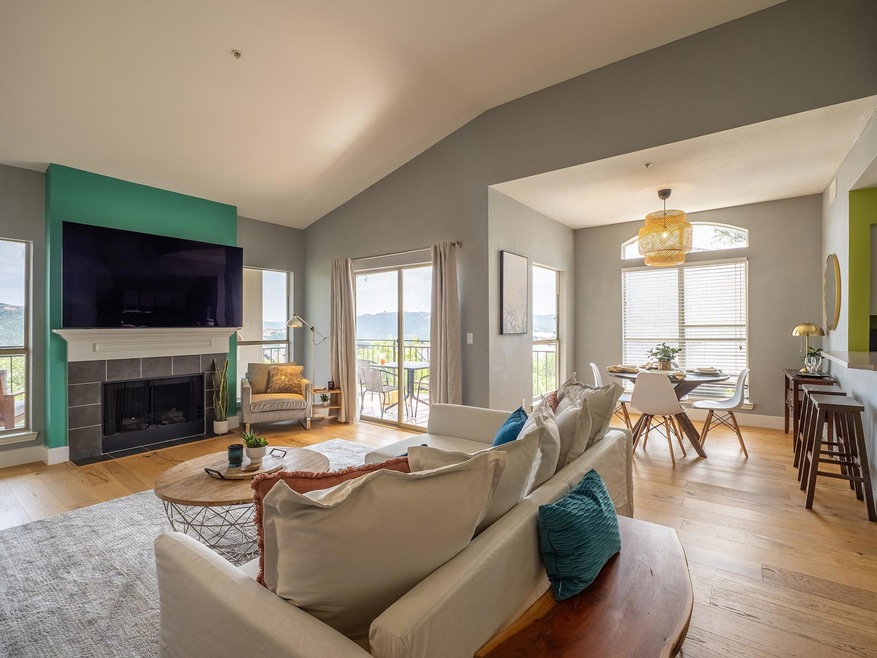 Living area featuring light wood-style floors, vaulted ceiling, and a tiled fireplace