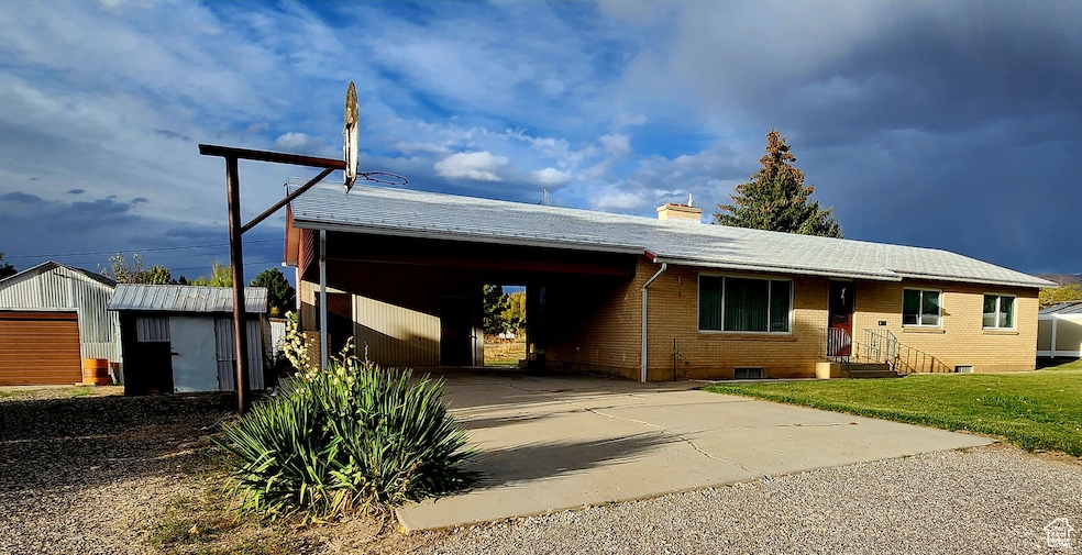 Ranch-style house with concrete driveway, a chimney, brick siding, an outbuilding, and an attached carport