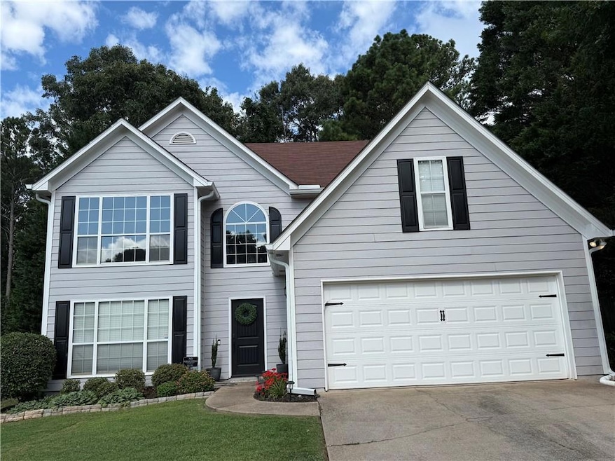 Traditional-style house with concrete driveway, an attached garage, and a front lawn