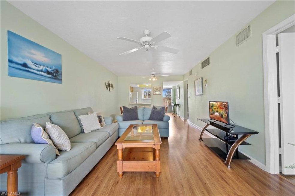 Living room with ceiling fan, light wood-style flo