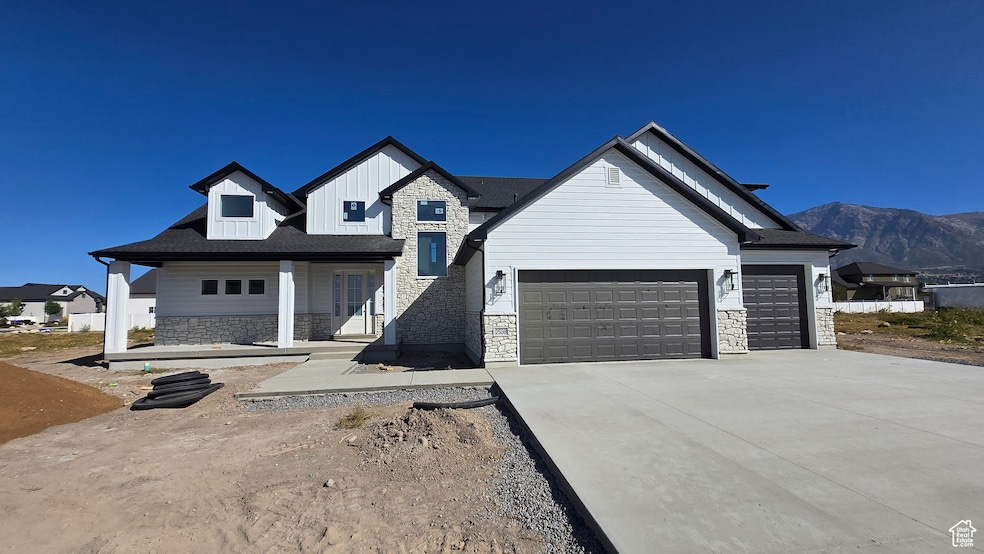 View of front of house featuring stone siding, covered porch, board and batten siding, driveway, and an attached garage
