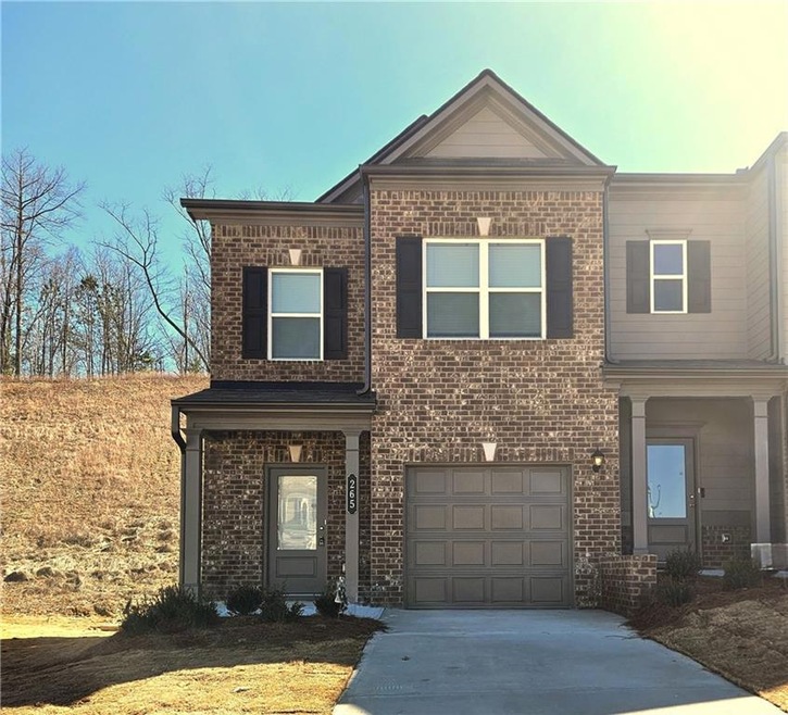 View of front of home featuring a garage, concrete driveway, and brick siding