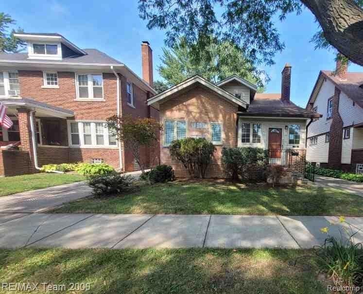 View of front of property with a chimney, brick siding, and a front lawn