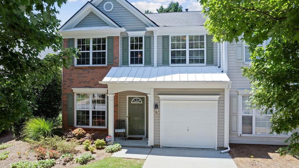 Traditional-style house with brick siding, driveway, a standing seam roof, a garage, and a shingled roof