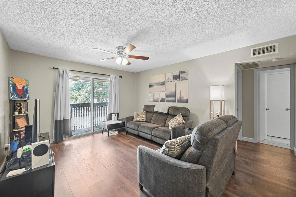 Living room featuring ceiling fan, a textured ceil