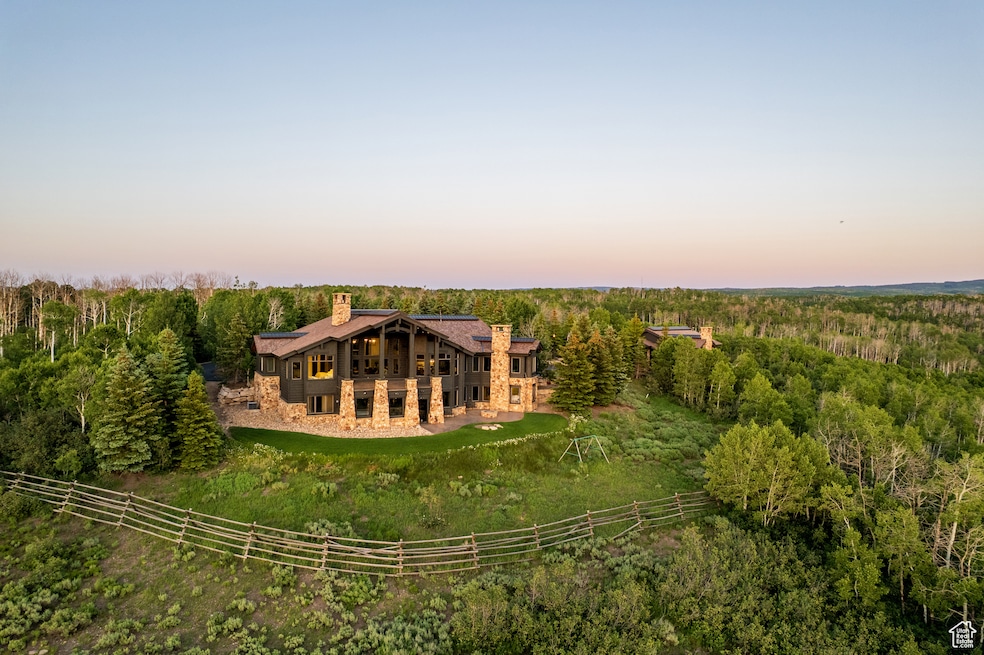 Back of house with a chimney, a wooded view, and stone siding