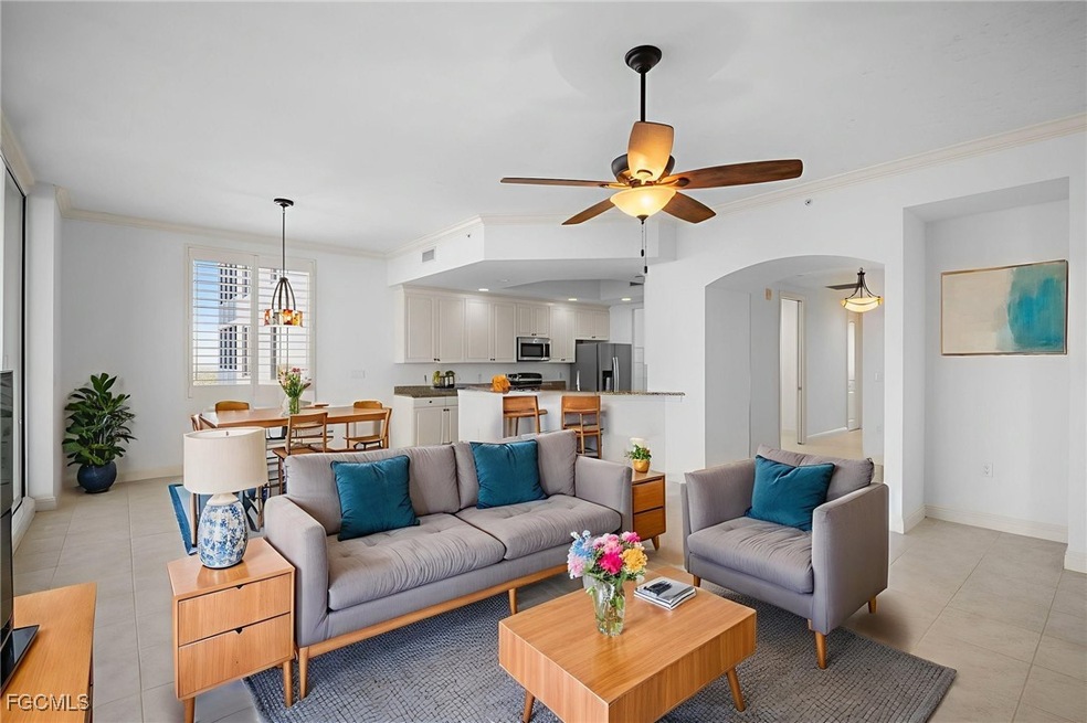 Living room featuring ceiling fan, light tile patterned floors, ornamental molding, a chandelier, and arched walkways