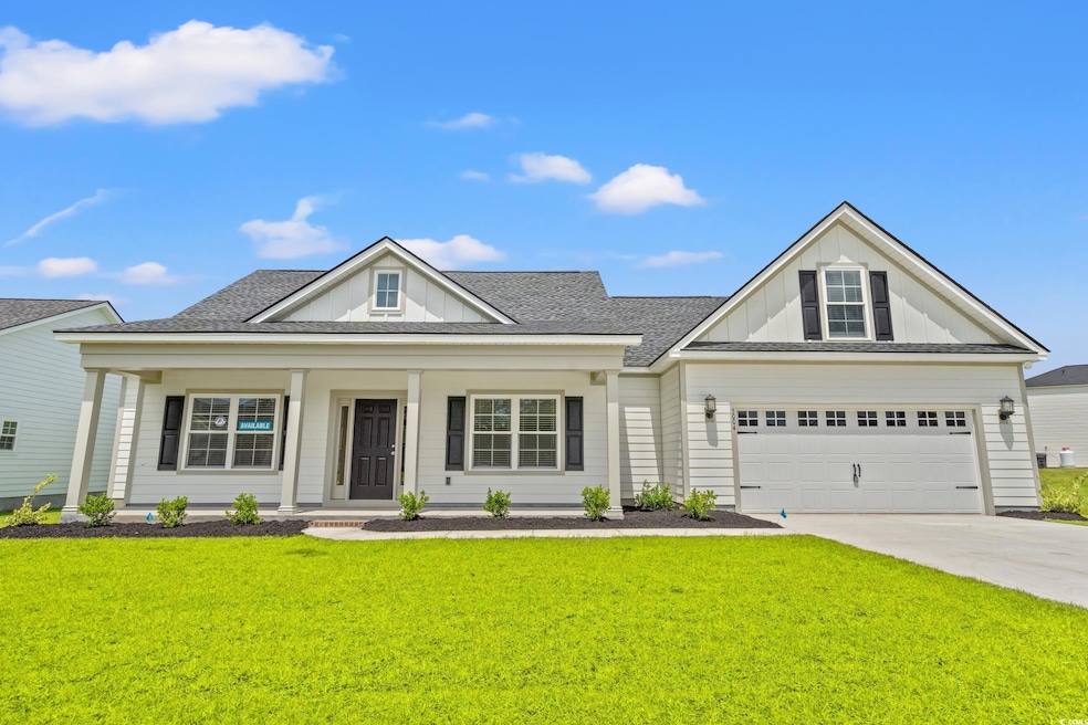 View of front facade with board and batten siding, driveway, a front yard, covered porch, and a shingled roof
