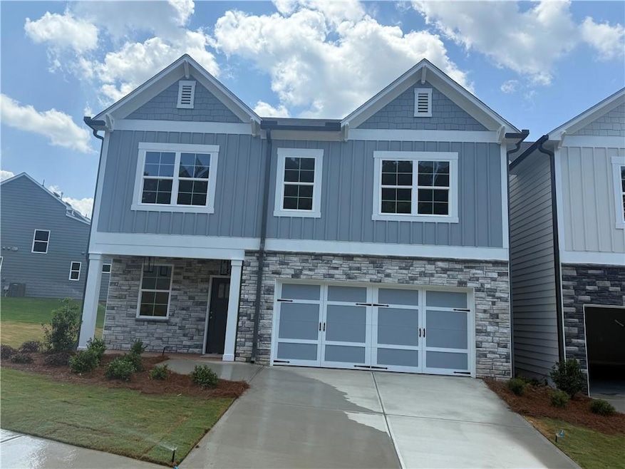 Craftsman-style home with board and batten siding, concrete driveway, and stone siding