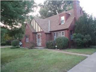 View of front of house. Mature trees on property. 
