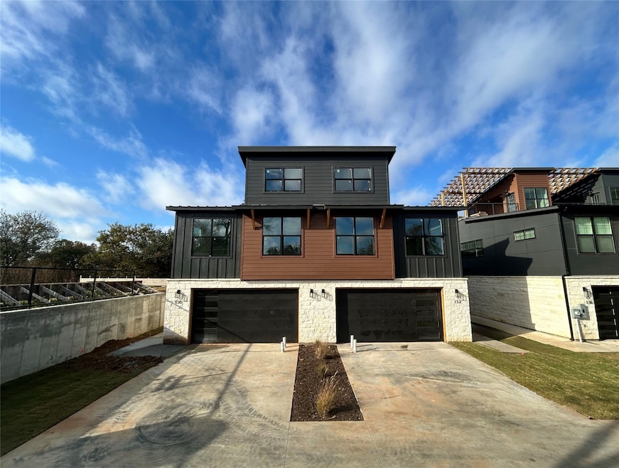 Contemporary house with stone siding, driveway, board and batten siding, and a garage