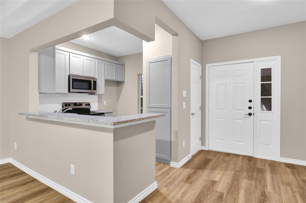 Kitchen with stainless steel appliances, light woo