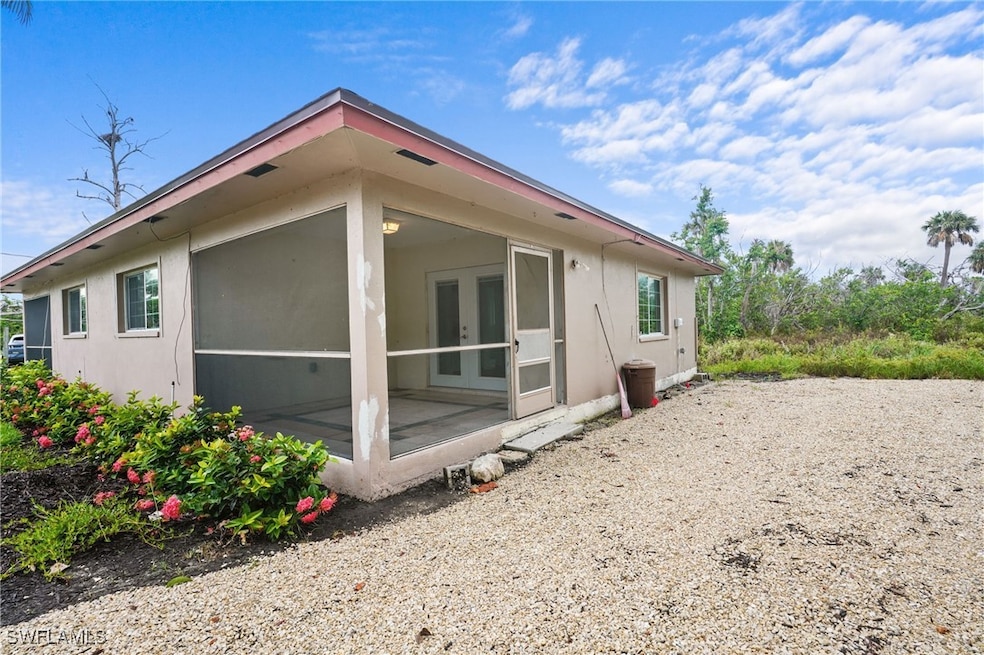 Back of house featuring a sunroom, stucco siding, and french doors