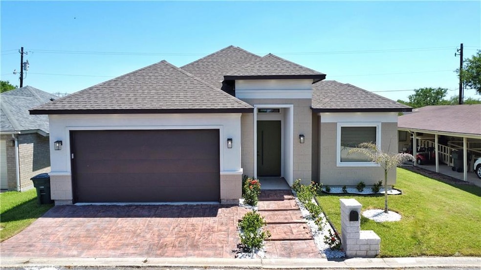View of front of house featuring a shingled roof, an attached garage, a front lawn, and driveway