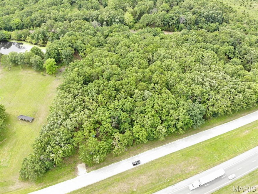 Drone / aerial view of a heavily wooded area and a nearby body of water