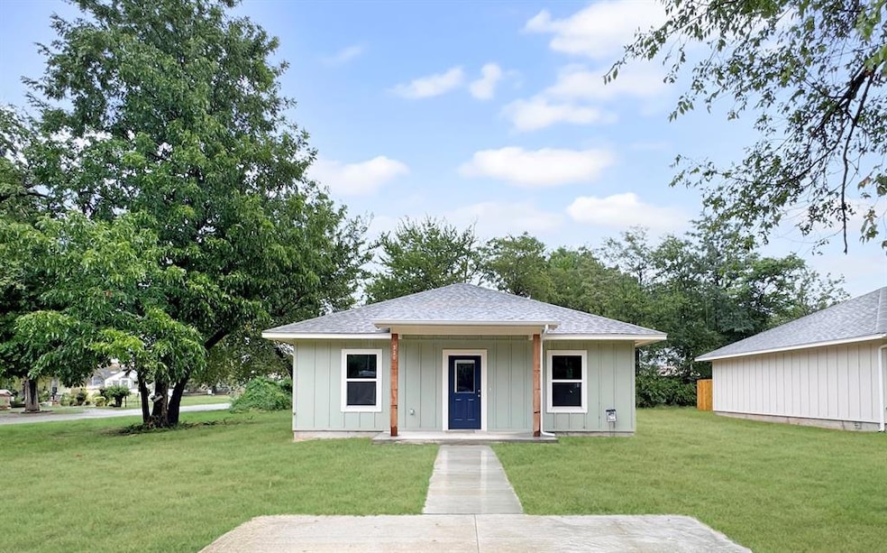 Front view of the home featuring a covered entry, neutral exterior, and spacious front yard. Note: Photos are of a similar home by the builder.