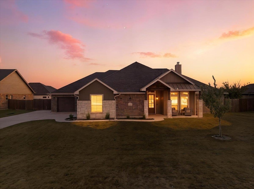 View of front of home featuring driveway, a chimney, stone siding, and an attached garage