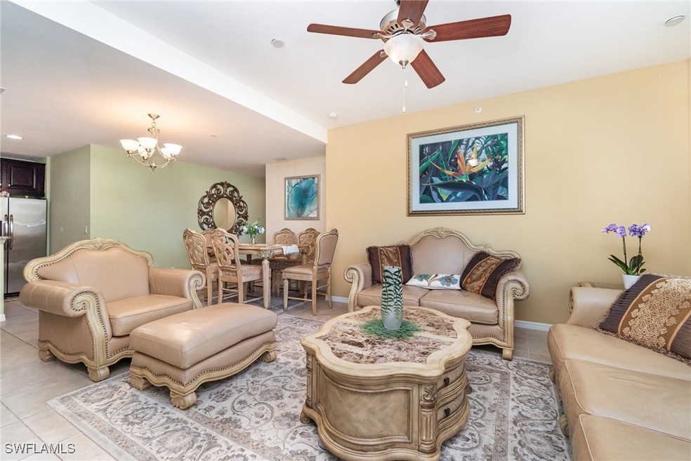Living area with light tile patterned flooring, ceiling fan, a chandelier, and baseboards